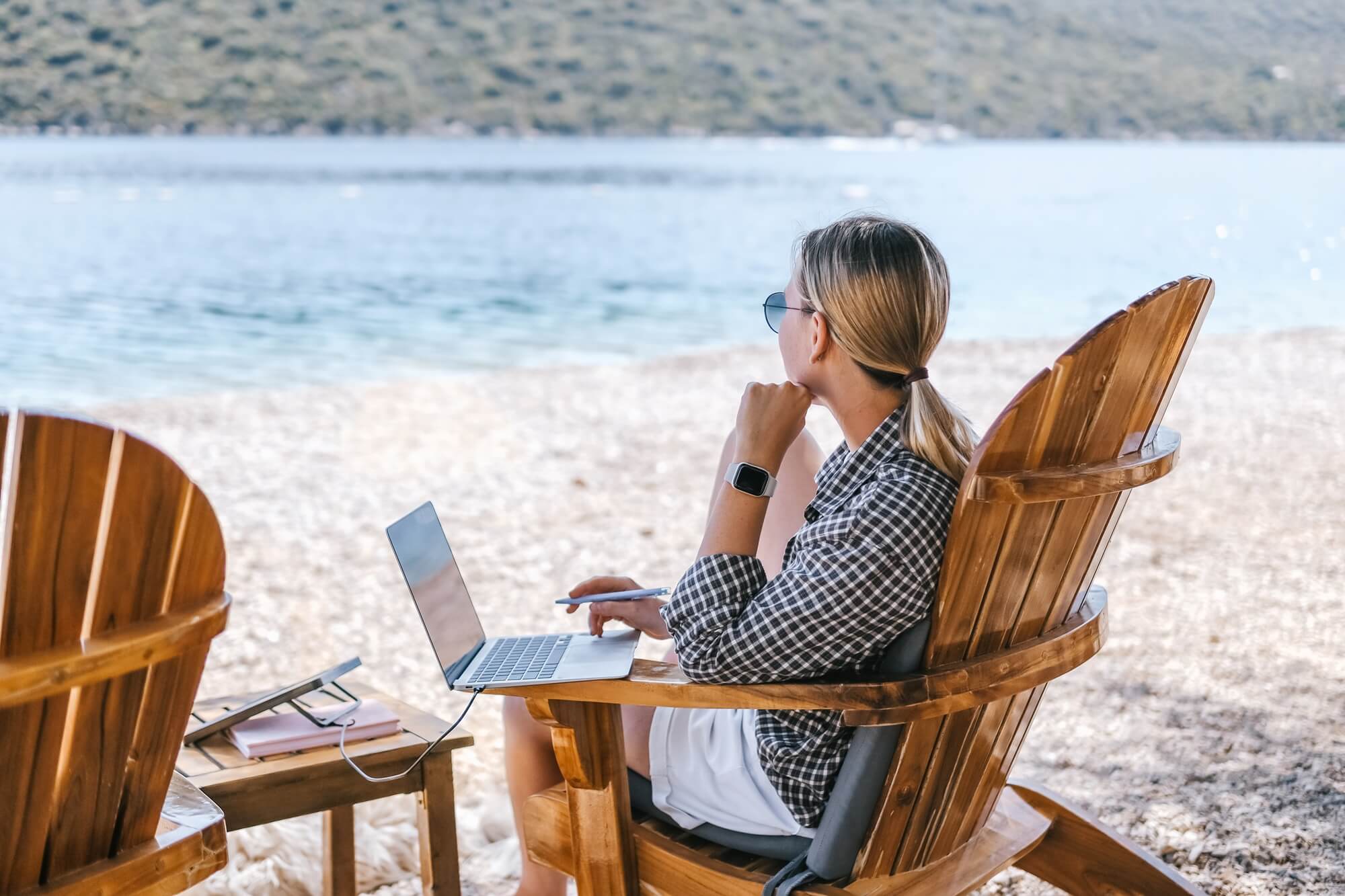 kobieta pracuje przy laptopie na plaży